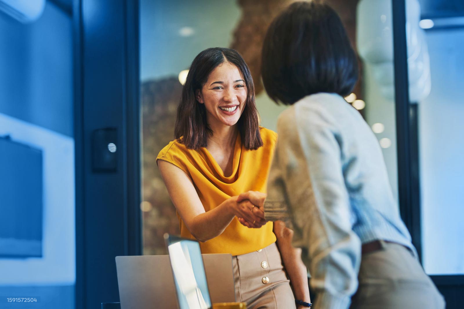 Woman smiling and shaking hands with another person